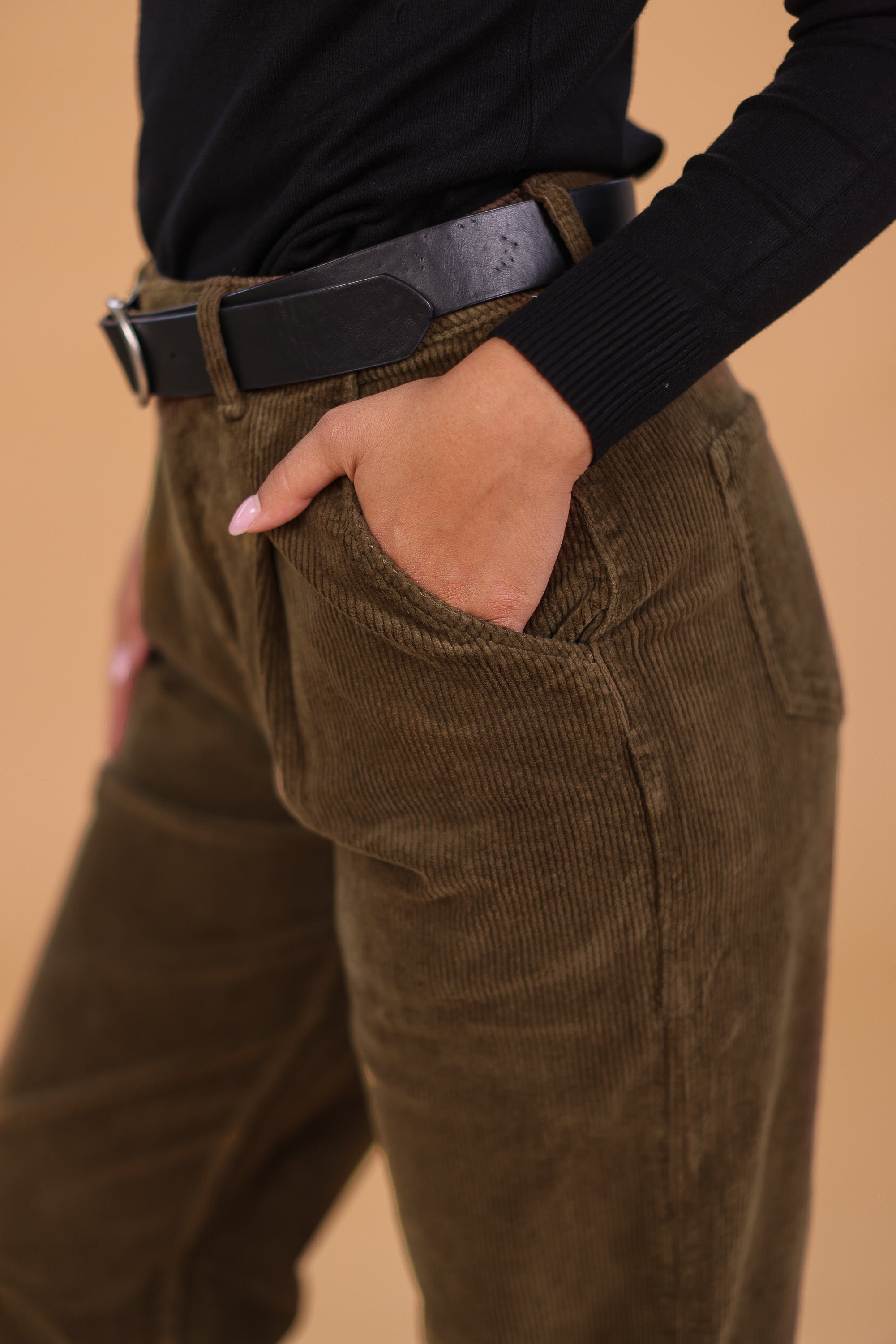 woman wearing khaki corduroy pants with a black belt