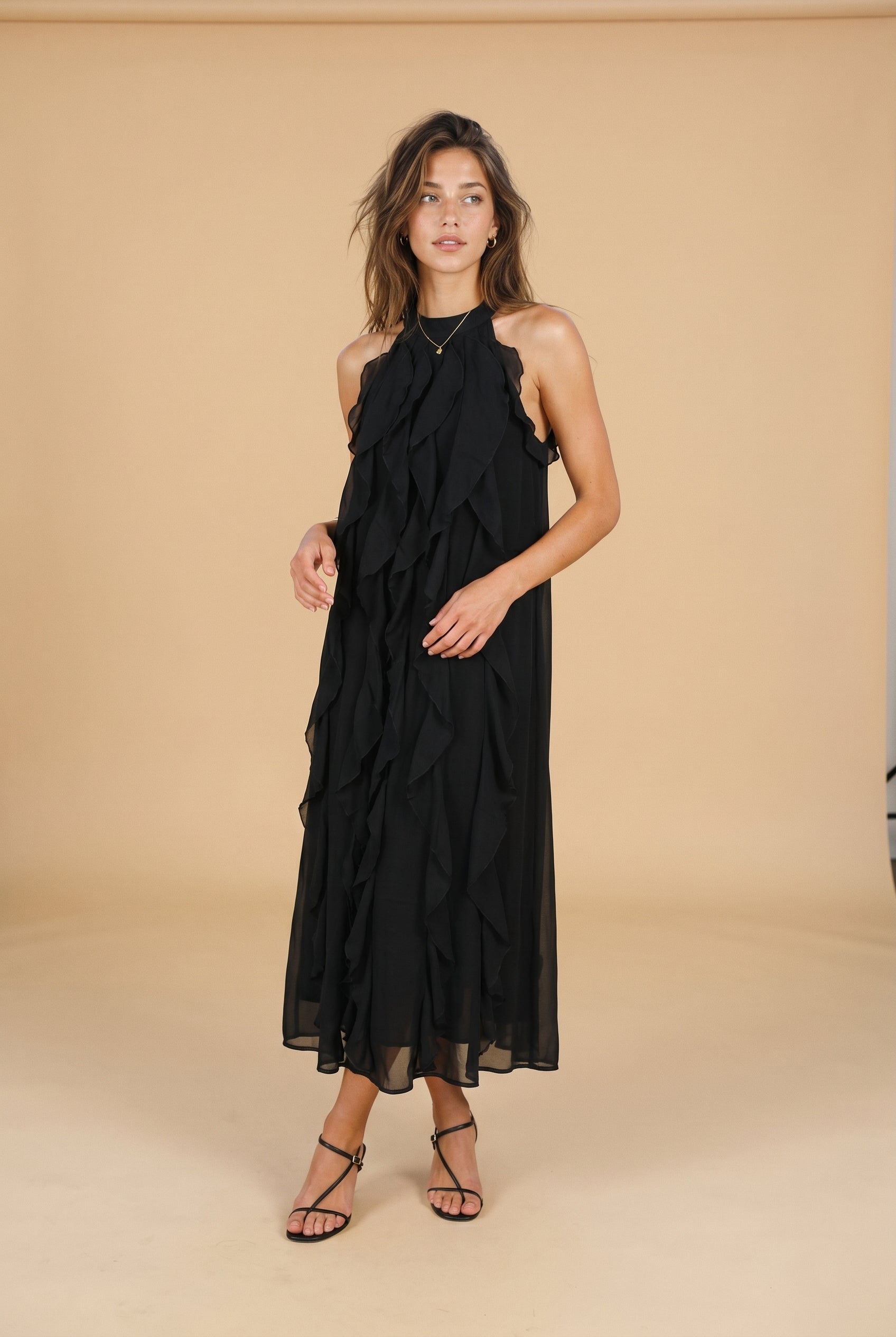 Woman wearing a black halter neck dress against a beige background