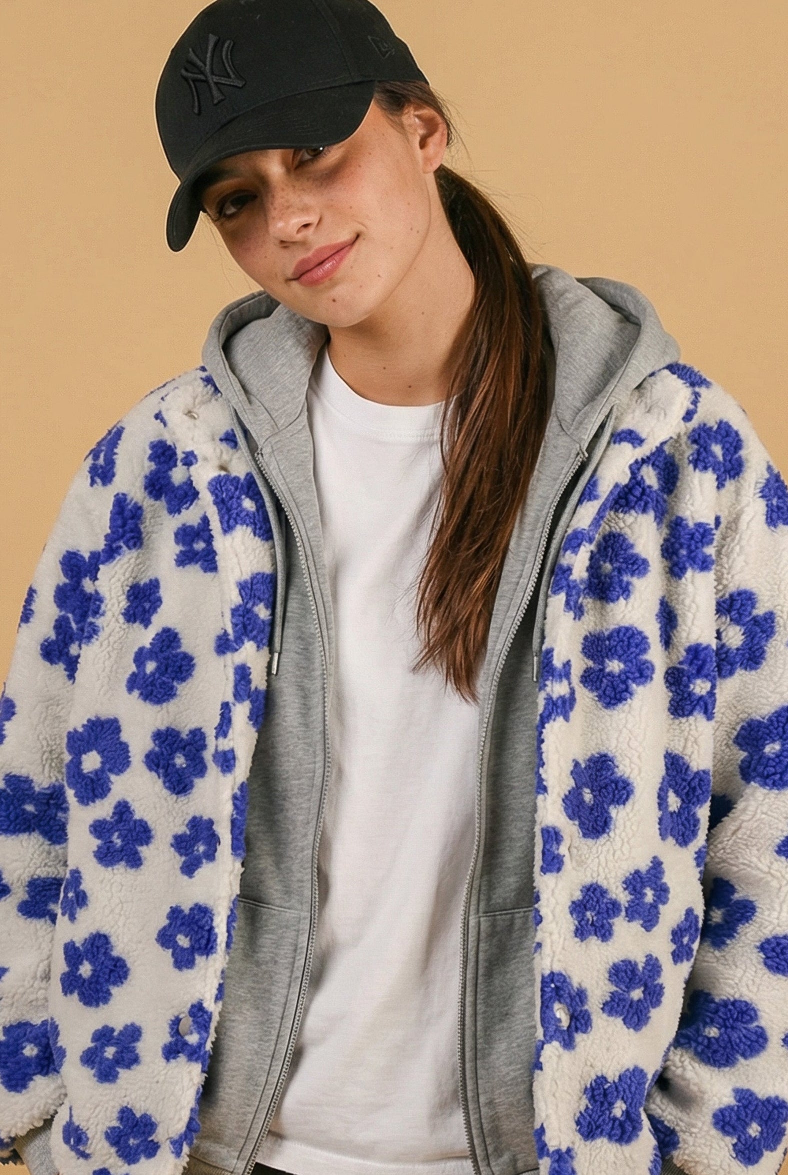 Person wearing a blue floral-patterned hoodie on a beige background